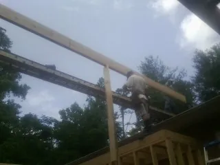 Carpenter setting a ridge beam over a new addition frame — Ice Dam Removal by Roofing Brothers in Townville