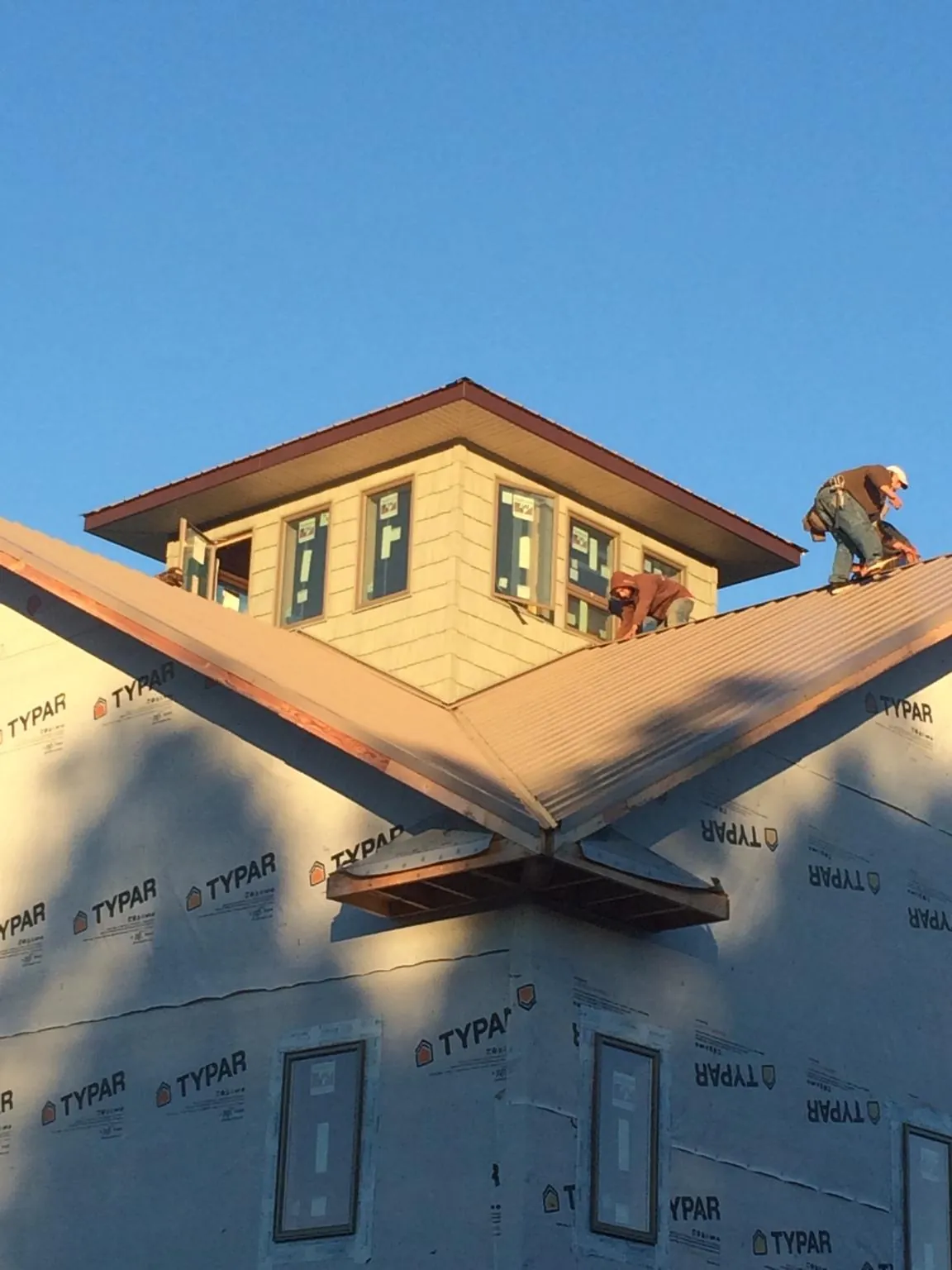 Roofers working around a rooftop cupola on a new metal roof at sunset — Roof Waterproofing in Townville by Roofing Brothers